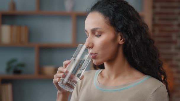 Healthy happy 30s Caucasian Hispanic woman with long hair perfect skin drinking still water at home has good habit holding glass drinking clean mineral natural h2o beverage feeling good freshness - Záběry, video