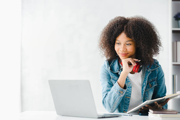 Американська дівчина-підліток, яка сидить у білому офісі з ноутбуком, вона є студенткою, яка навчається в Інтернеті з ноутбуком вдома, студенткою, яка навчається в Інтернеті, онлайн-концепції веб-освіти. - Фото, зображення