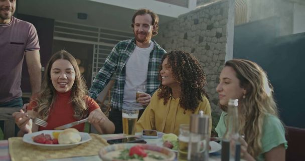 Familienmitglieder und Freunde zusammen zu Hause Hinterhof beim Grillen in Gartenparty. Fröhliche Menschen reden und lachen - Foto, Bild