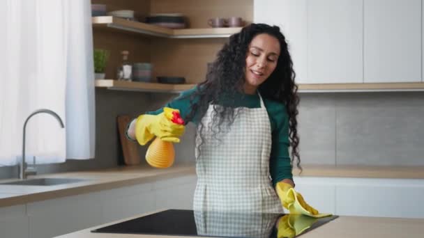 Happy young housewife arabian woman domestic cleaner maid in yellow gloves cleaning apartment washing oven by rag splashing detergent spray dancing rhythmic moves to favorite music enjoy house chores - Video
