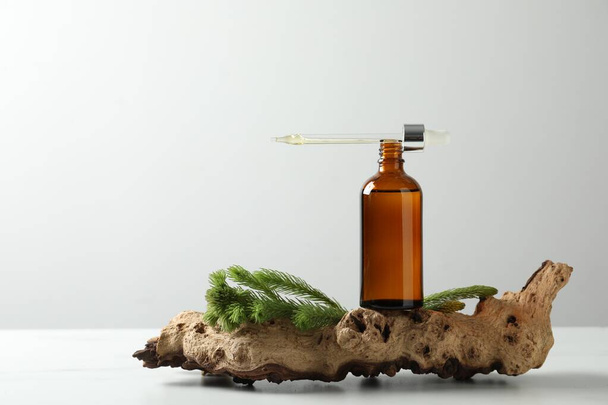 Bottle of hydrophilic oil and fir twigs on white background, space for text - Valokuva, kuva