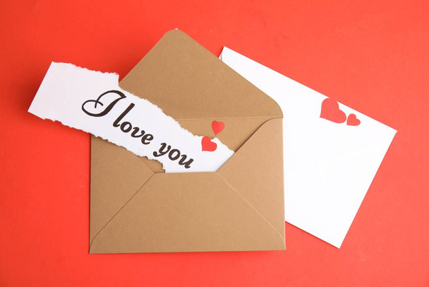 Sheet of paper with phrase I Love You and envelopes on red background, flat lay - Foto, Bild