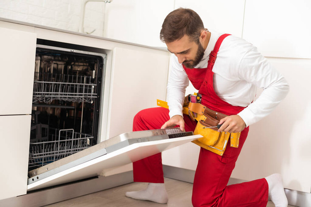 Technician or plumber repairing the dishwasher in a household. - 写真・画像