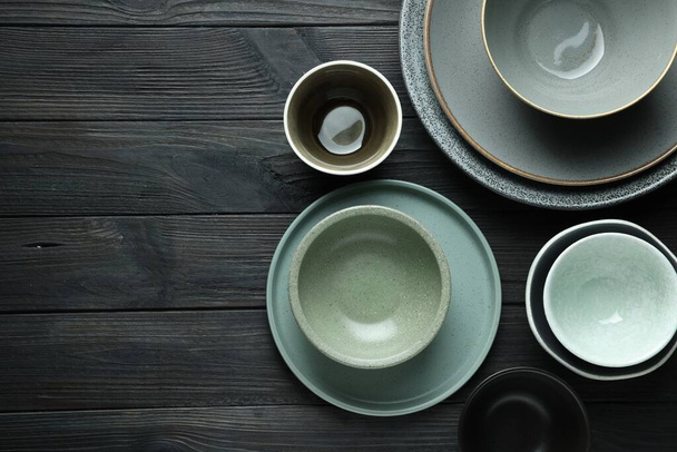 Stylish empty dishware on black wooden table, flat lay. Space for text - 写真・画像