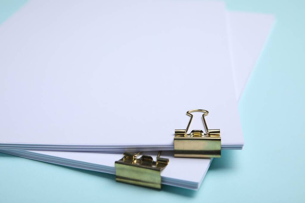 Sheets of paper with clips on light blue background, closeup - Fotografie, Obrázek