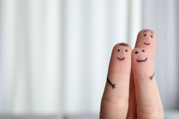 Three fingers with drawings of happy faces on blurred background, space for text - Fotoğraf, Görsel