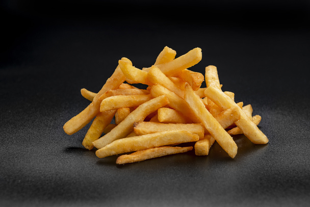 Pile of french fries over black background. Photo for the menu - Foto, immagini