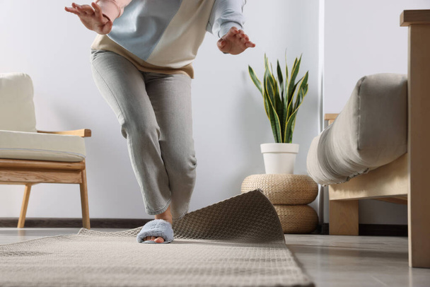 Woman tripping over carpet at home, closeup - Фото, зображення