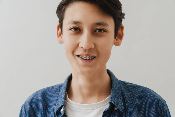 Asian boy with dental braces smiling and looking at camera isolated over white background - Foto, immagini