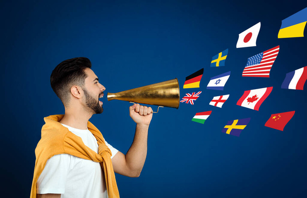 Portrait of interpreter with megaphone and flags of different countries on blue background - Foto, Imagem