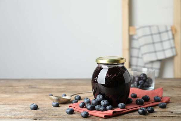 Jar of blueberry jam and fresh berries on wooden table. Space for text - Foto, imagen
