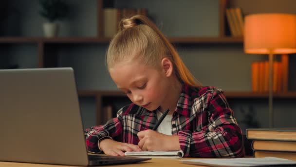 Caucasian kid girl preschool child pupil studying online from home write homework at copybook watch web class lesson learn by video call self-education in pandemic isolation listen educational tutor - Filmmaterial, Video