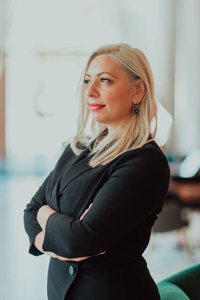 Portrait of a business senior woman with crossed arms standing in a modern corporation. Selective focus. High quality photo - Фото, изображение