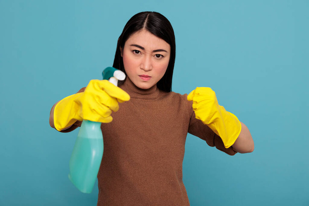 Aggressive overwhelmed asian young housemaid in rubber gloves and detergent spray standing in a fight pose, Cleaning home concept, Confidence energetic housekeeper feeling negative - Φωτογραφία, εικόνα