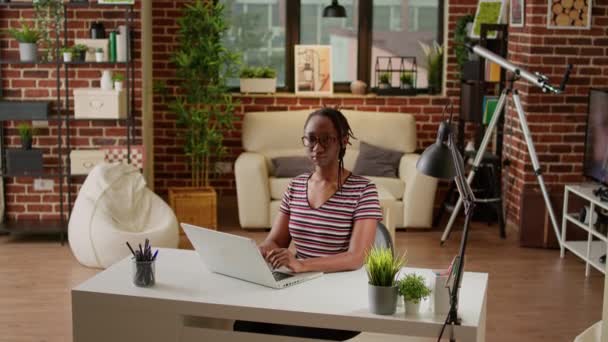 Portrait of african american freelancer working from home, using laptop at desk to do startup job. Female employee attending online webinar remotely from living room, business work. - Filmmaterial, Video