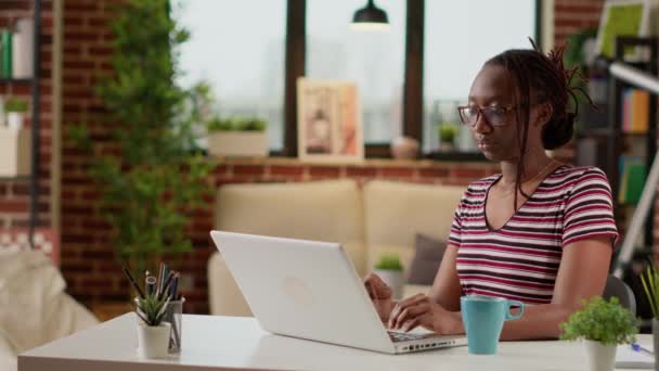 Afrikkalainen freelancer kirjoittaa tietoja kannettavalla, työskentelee etänä kotitiskiltä. Nuori nainen selailee internetiä tietokoneella tehdä etätyötä, kaukainen online-liiketoiminnan työtä. Kolmijalka laukaus. - Materiaali, video