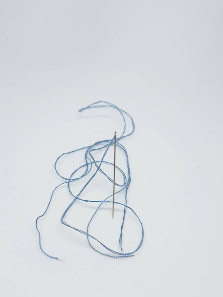 A sewing needle with a light blue thread attached to it. Needles stand upright, ready for sewing. - Fotó, kép