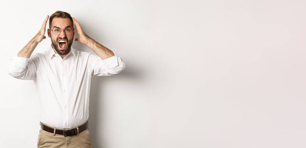 Frustrated man panicking, shouting and looking anxious, standing over white background. - Fotografie, Obrázek