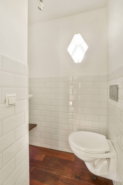 Wall hung toilet and small sink in corner in lavatory room with tile - Фото, зображення