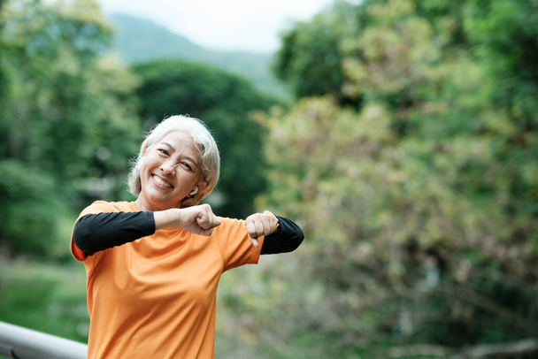 Happy athletic Senior woman in park before running in park, health concept. - Foto, afbeelding