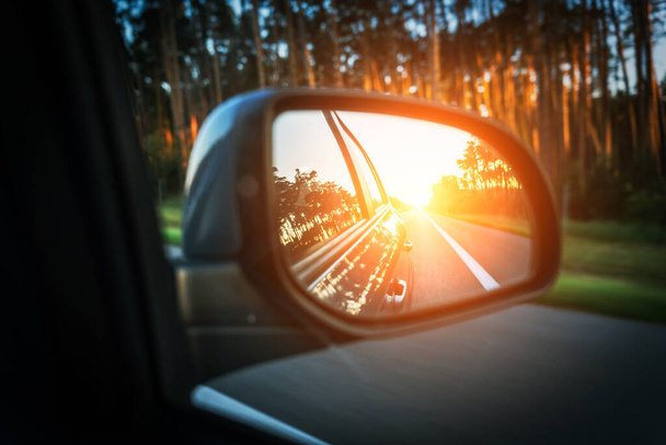 Ταξίδι ηλιοβασίλεμα αυτοκίνητο καθρέφτη. Η αντανάκλαση του αυτοκινητόδρομου στον καθρέφτη. Καλοκαιρινό ταξίδι έννοια - Φωτογραφία, εικόνα