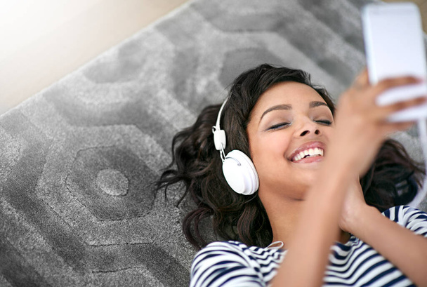 Melodic moments. a young woman listening to music at home - Foto, Imagen
