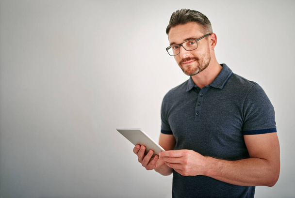 There are so many great apps to choose from. a man using a digital tablet against a gray background - Foto, Bild