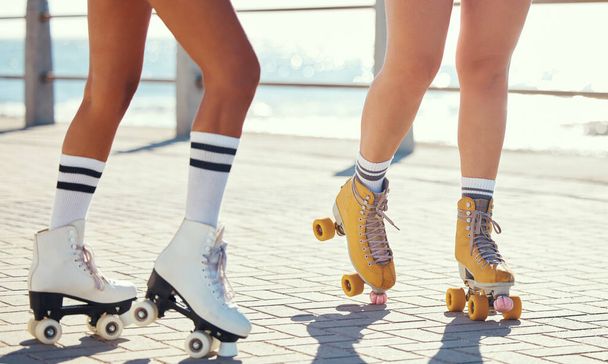 Roller skates or fun friends on promenade for summer holiday activity or travel outdoor. Cool, trendy or funky women skating legs in quad skating or rollerblades with sunshine, beach and ground. - Photo, image