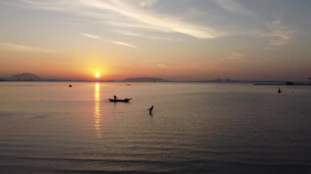 Slowly move toward fisherman catch fish with net in early morning. Background is Penang Bridge - 映像、動画