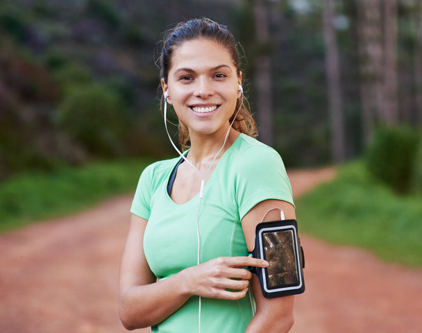 Getting ready for some action with the right playlist. a young woman listening to music while out running - Zdjęcie, obraz
