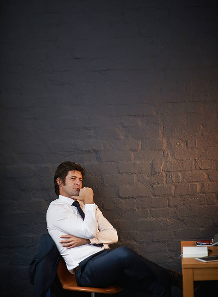 Thinking about business. a businessman looking thoughtful while sitting in his office late at night - 写真・画像