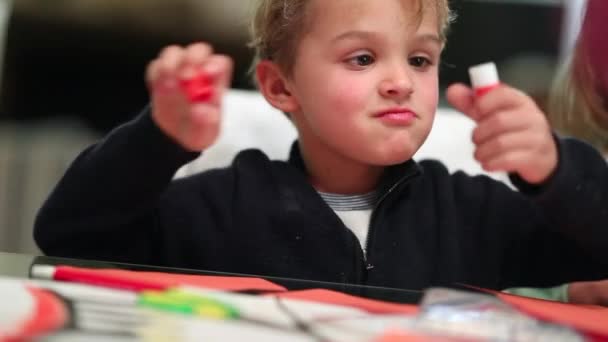 Child toddler uncorking glue, infant boy child untwisting glue crafting work - Footage, Video
