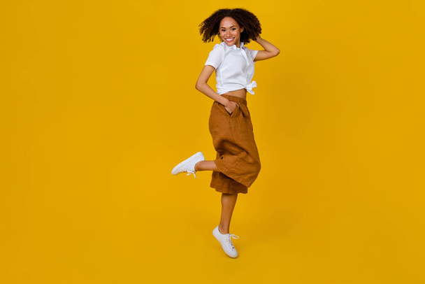 Full body photo of excited carefree lady arm touch hair good mood jumping isolated on yellow color background. - Foto, Imagen