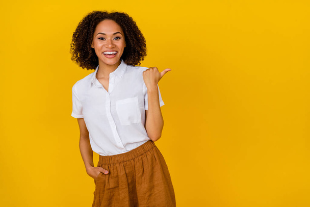 Photo of cheerful pretty female person promote you good quality clothes shop point empty space isolated on yellow color background. - Photo, Image