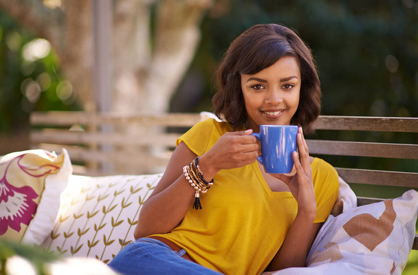 Just me and a cuppa tea. a young woman relaxing with a beverage in the backyard - 写真・画像