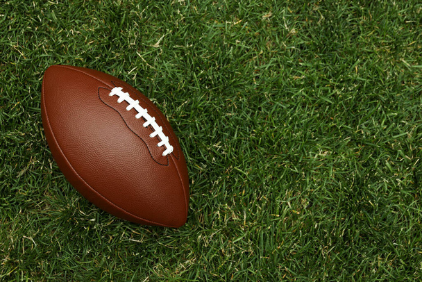 American football ball on green grass background - Valokuva, kuva