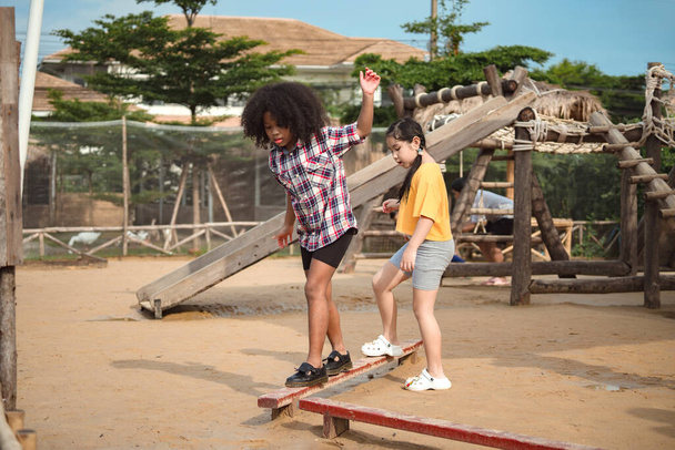 Two girl kid walks on a log, keeping her balance, walking on the playground. - Photo, Image