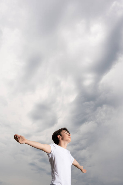 Teenager boy breathing and meditating under dramatic stormy sky. - Foto, Imagem