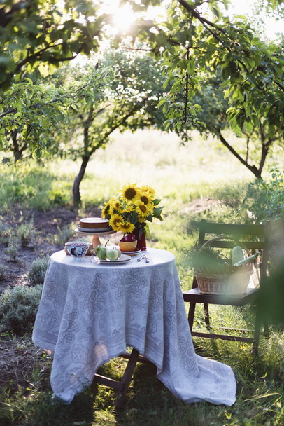 garden and still life. tea party in the garden - pie, vase with sunflowers and apples on a table - Foto, Bild