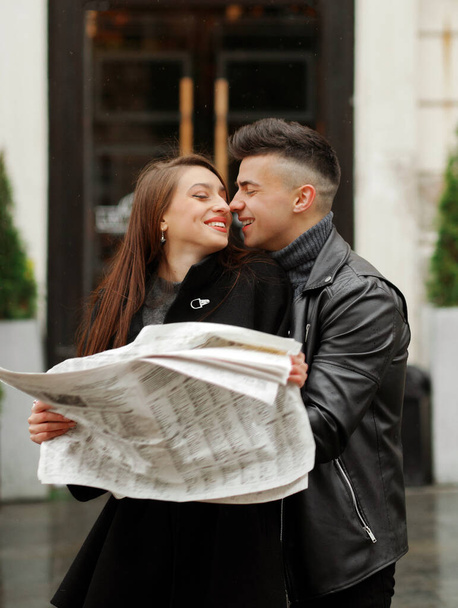 Молода пара тримає газету в руках на фоні кафе
 - Фото, зображення