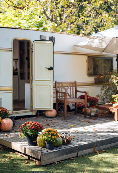 Caravan mobile home with terrace, Mobile home decorated with autumn decor. Cozy atmosphere - flowers, fallen leaves, pumpkins. Caravan camping. mobile home trailer. - Valokuva, kuva