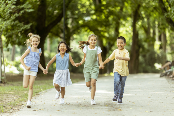 Група милих азіатських і кавказьких дітей розважаються в парку
 - Фото, зображення
