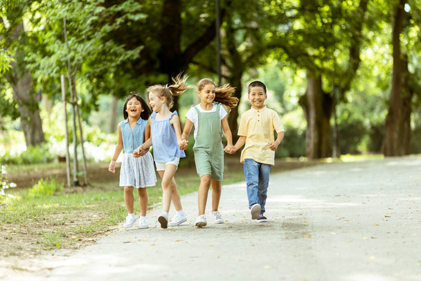 Група милих азіатських і кавказьких дітей розважаються в парку
 - Фото, зображення