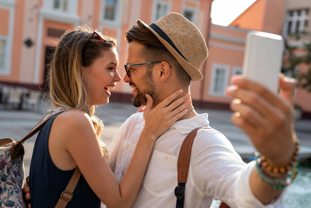 Happy traveling young couple taking selfie, having fun on vacation. People technology happiness concept. - 写真・画像