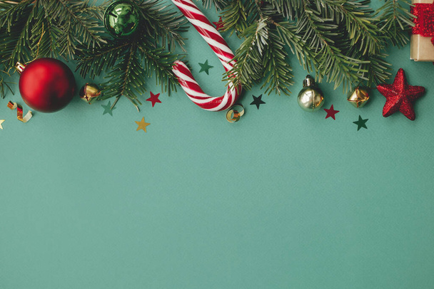 クリスマス・フラット・レイ。スタイリッシュなクリスマスのお祝いの装飾、コンフェッティ、緑の背景にモミの枝。季節ごあいさつカードテンプレート、テキストのためのスペース。メリークリスマスとハッピーホリデー! - 写真・画像