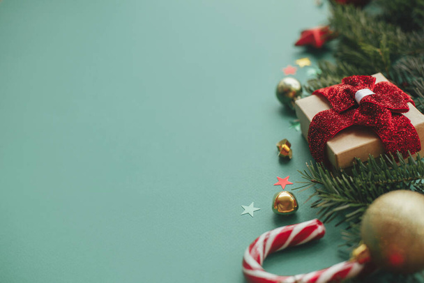 Frohe Weihnachten! Modernes Weihnachtsbanner. Stilvolle Weihnachtseinfassung mit festlicher Dekoration, Konfetti, Tannenzweigen, Geschenk auf grünem Hintergrund. Jahreszeiten-Grußkarten-Vorlage, Platz für Text - Foto, Bild