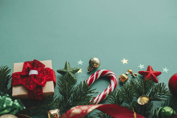 ¡Feliz Navidad! Banner navideño moderno. Elegante borde de Navidad con decoraciones festivas, confeti, ramas de abeto, regalo sobre fondo verde. Plantilla de tarjeta de felicitación Seasons, espacio para texto - Foto, Imagen