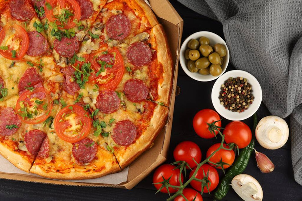 Pizza in a box on the table. Hot pizza with vegetables. Pizza in a restaurant. - Foto, Imagem