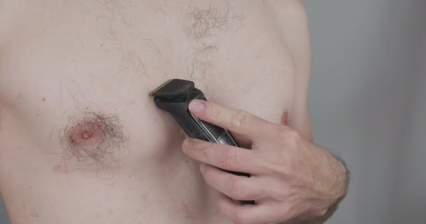 Young caucasian man shaving his chest with a trimmer. Side view, close-up. High quality 4k footage - Filmmaterial, Video