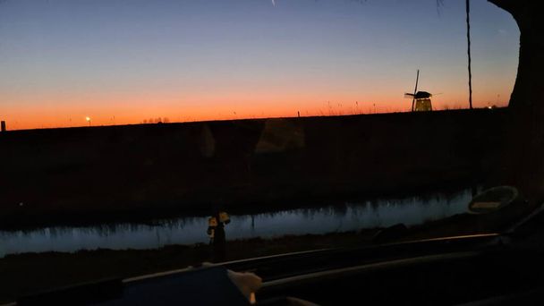 Camper van in the sunset in the background a Dutch windmill  - Foto, imagen
